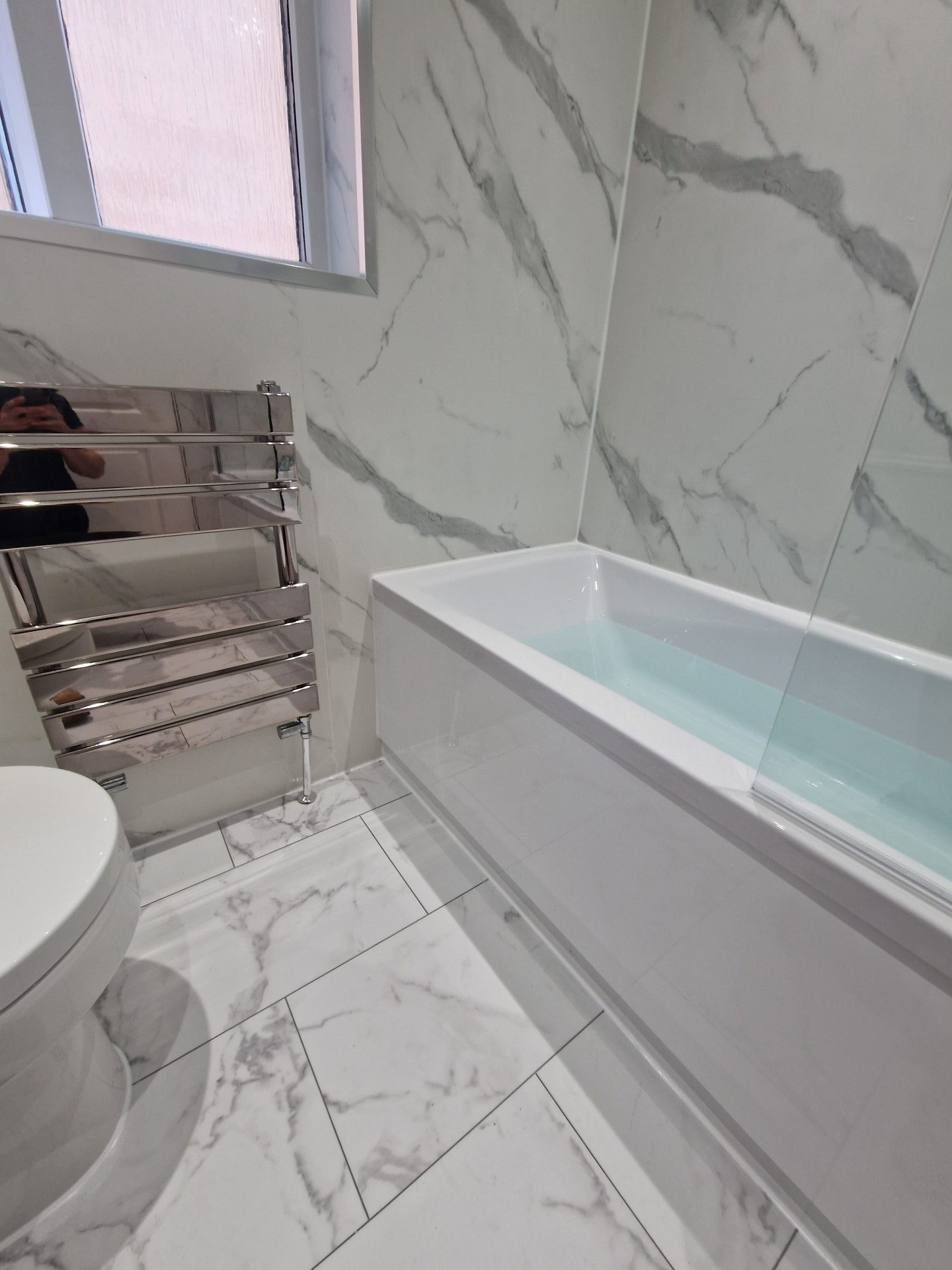 Bathroom with a bathtub, modern toilet, and heated towel rail